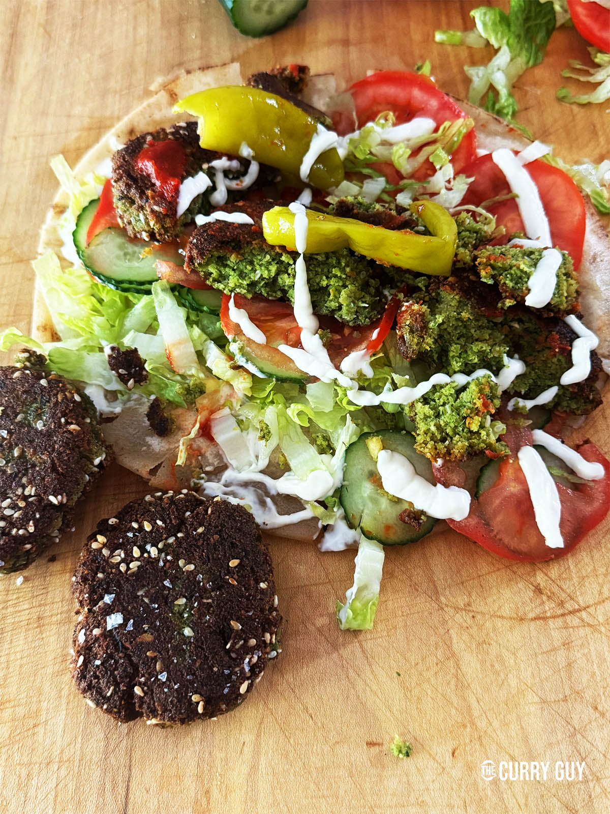 Felafel on a flatbread with salad vegetables, taum and kebab shop red sauce. 