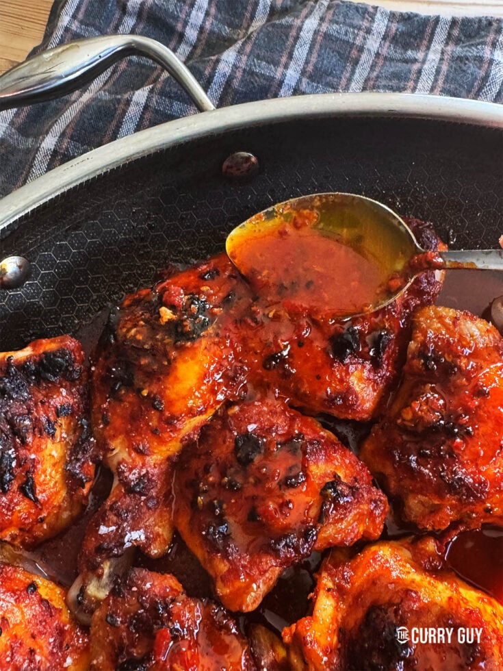 Basting harissa chicken in a pan.