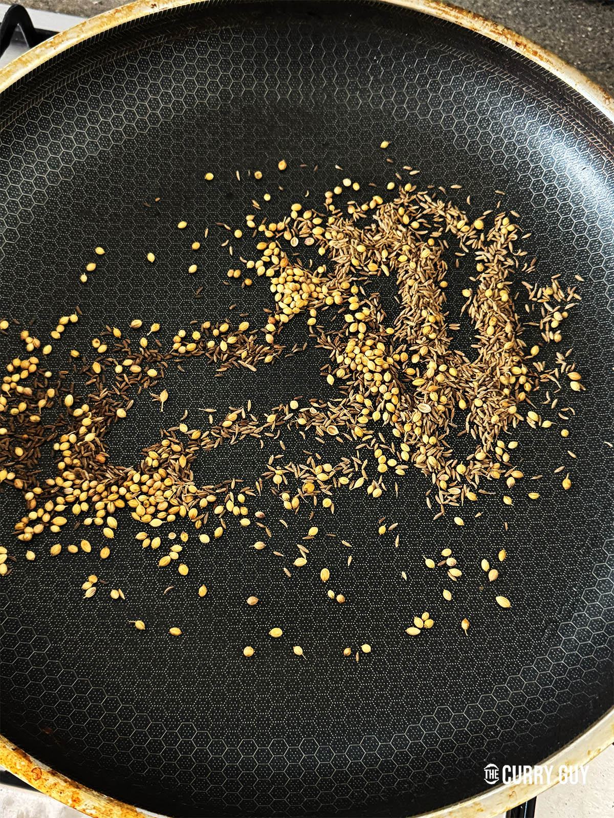 Toasting the cumin seeds, coriander seeds and caraway in a dry frying pan.