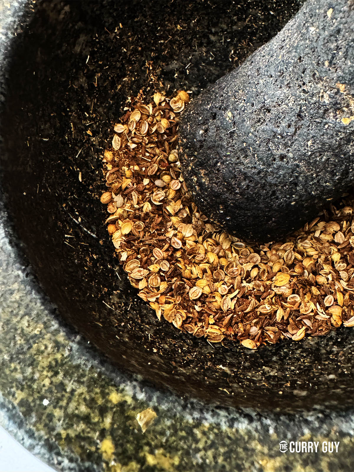 Grinding the whole spices in a pestle and mortar.