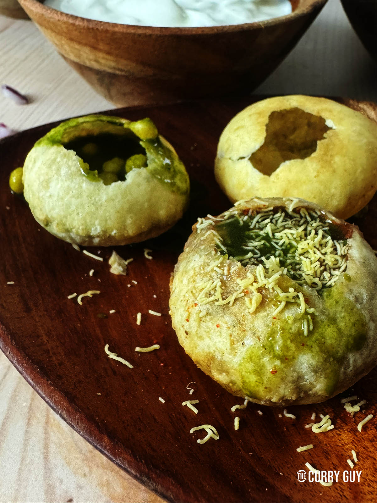 The pani puris filled with potatoes, onion, chickpeas, yoghurt and green and black pani.