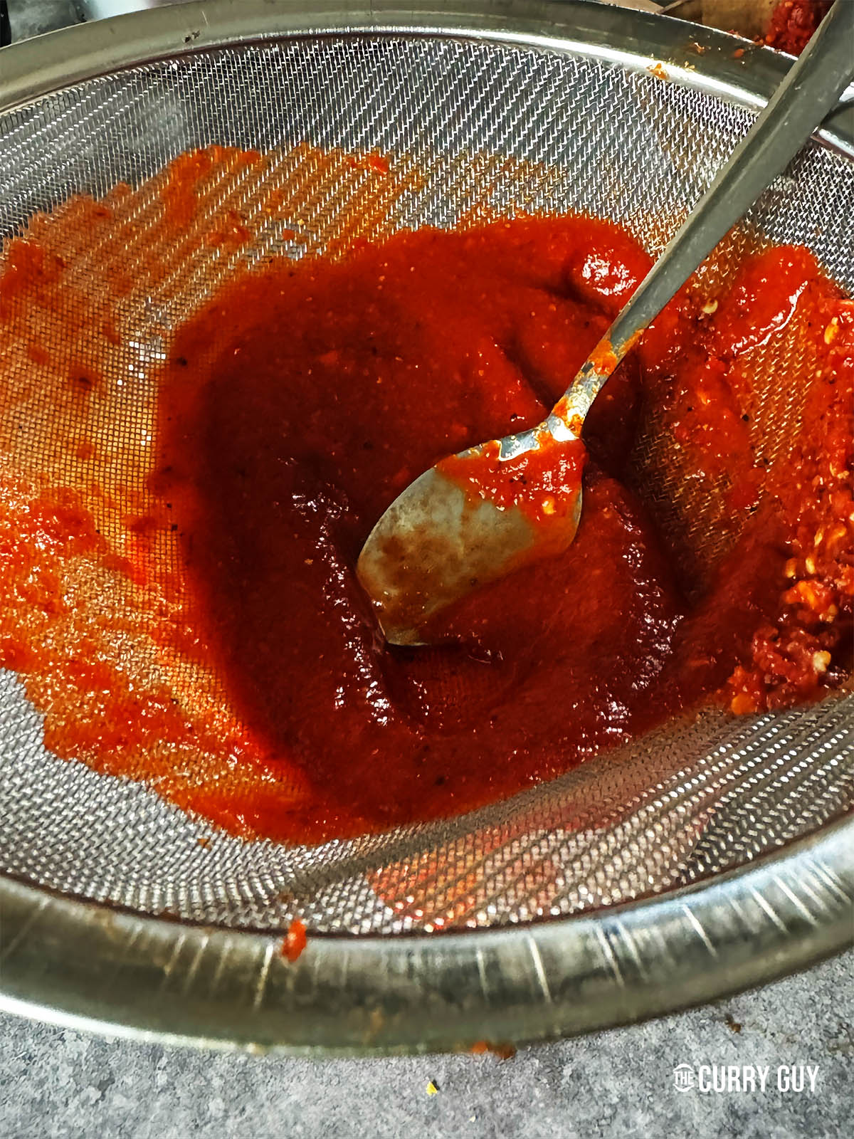 Running the sauce through a fine seive.