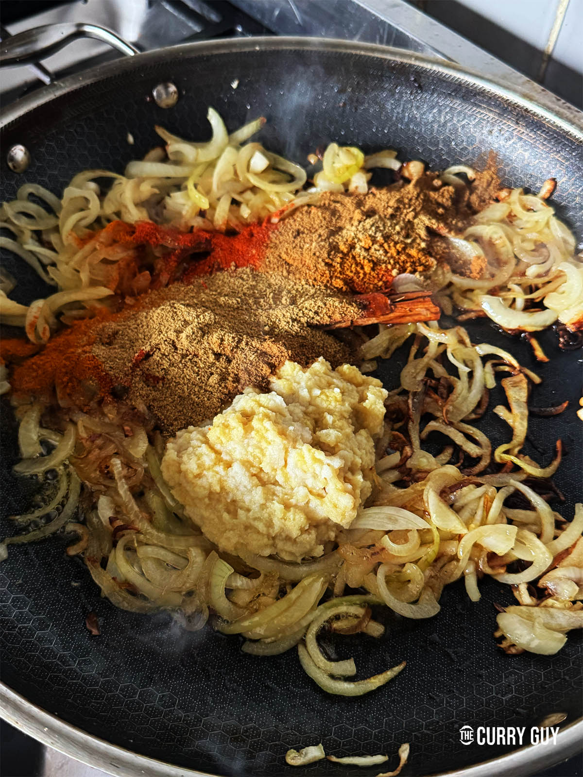 Adding the garlic and ginger paste and the ground spices to the pan.
