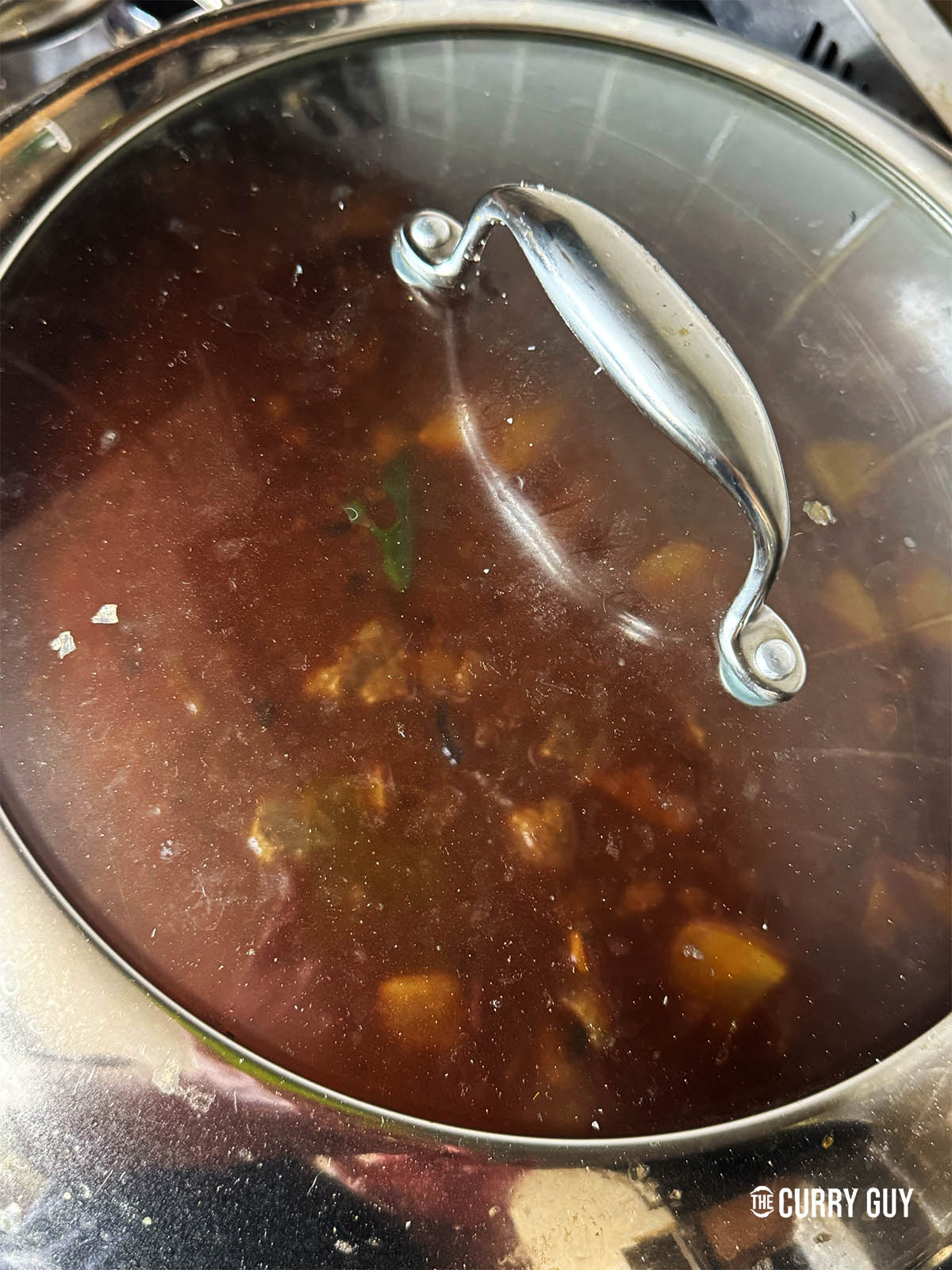 Covering the curry to simmer for 2 hours.