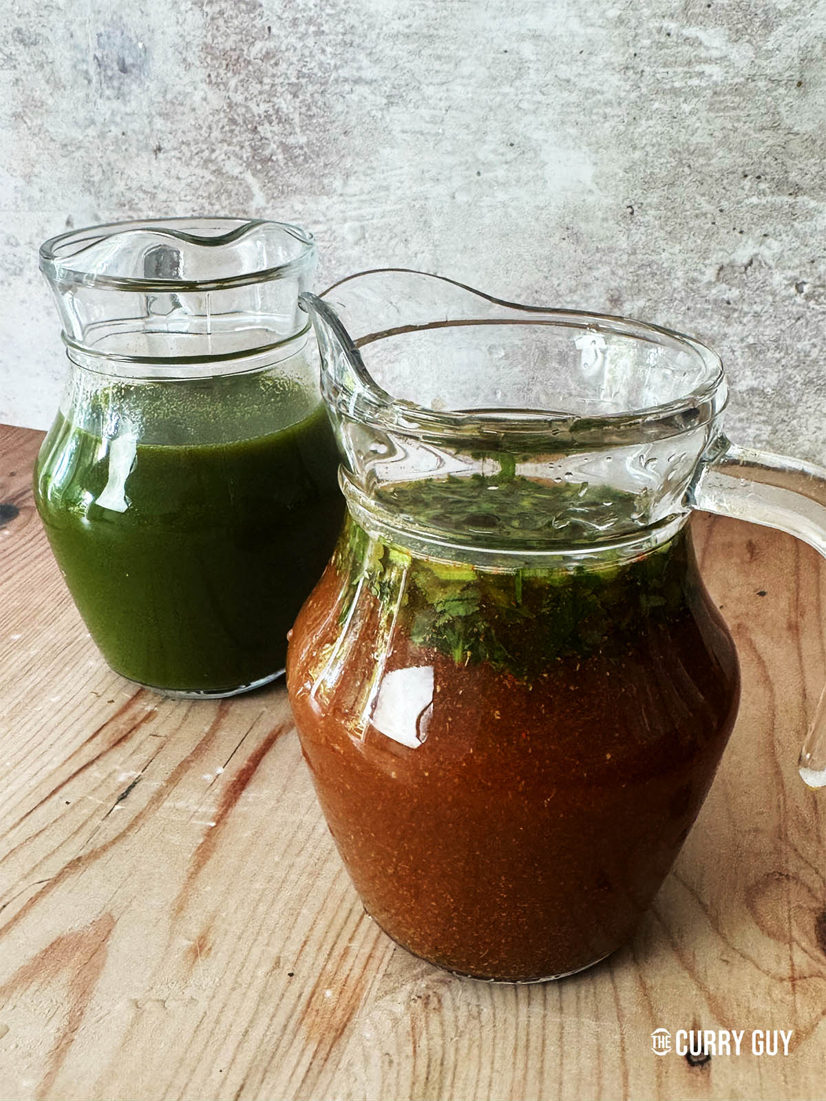 Tamarind water in a bottle next to a bottle of green pani.