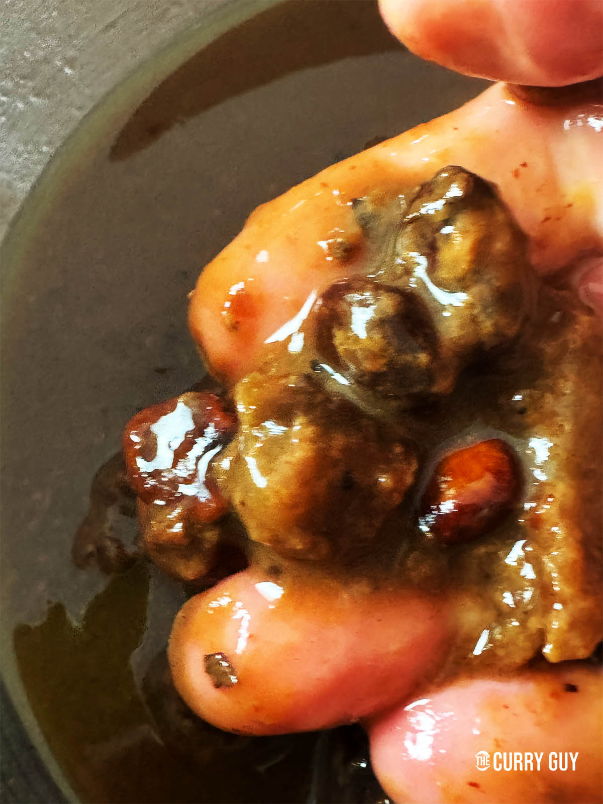 A hand holding the seeds from the block tamarind.