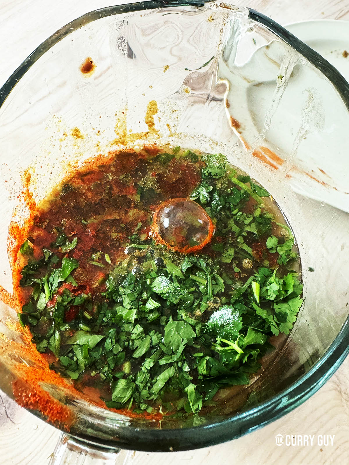 Adding the spices, mint sauce and chopped coriander to the tamarind water.
