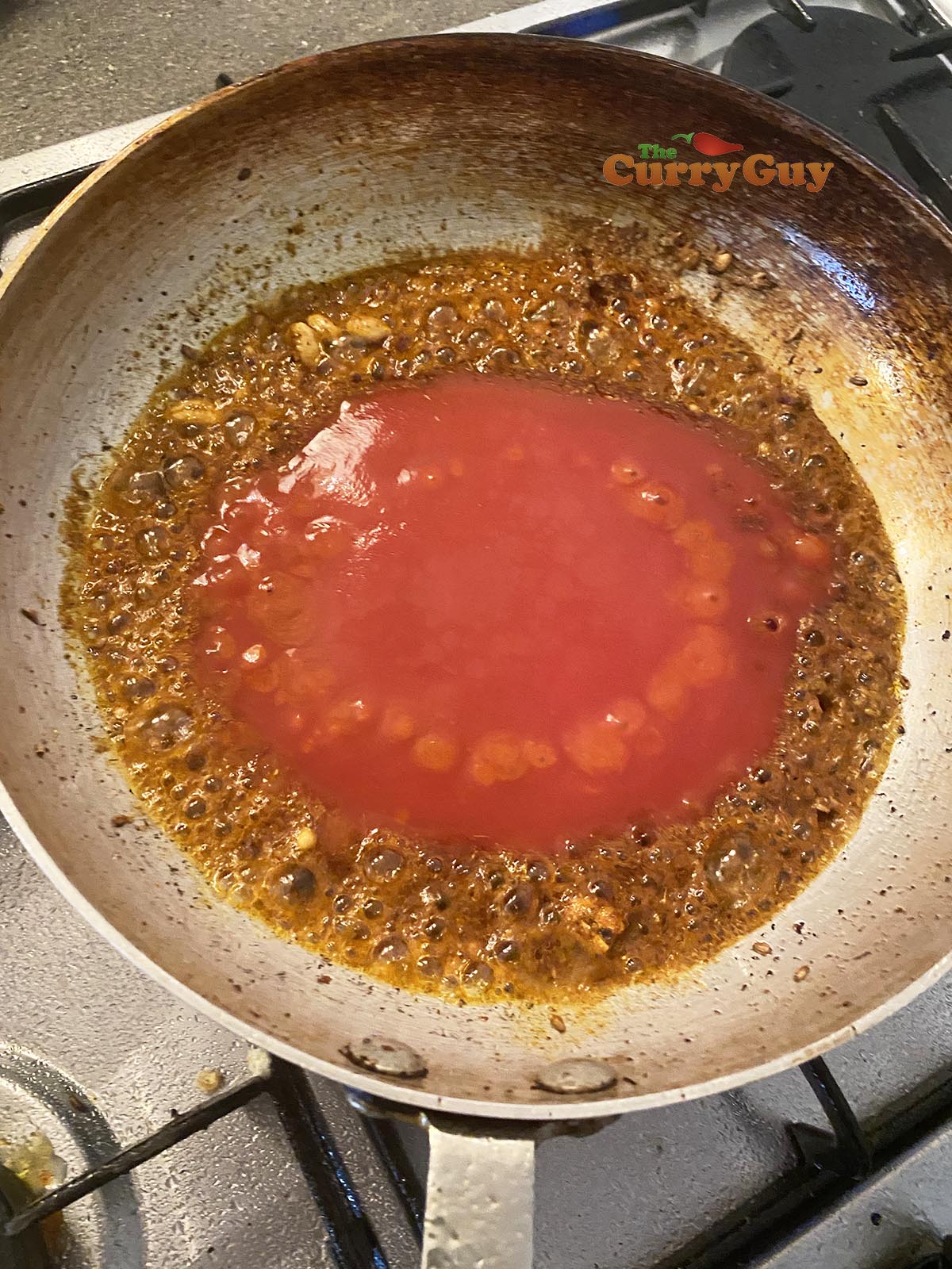 adding tomato puree to the pan