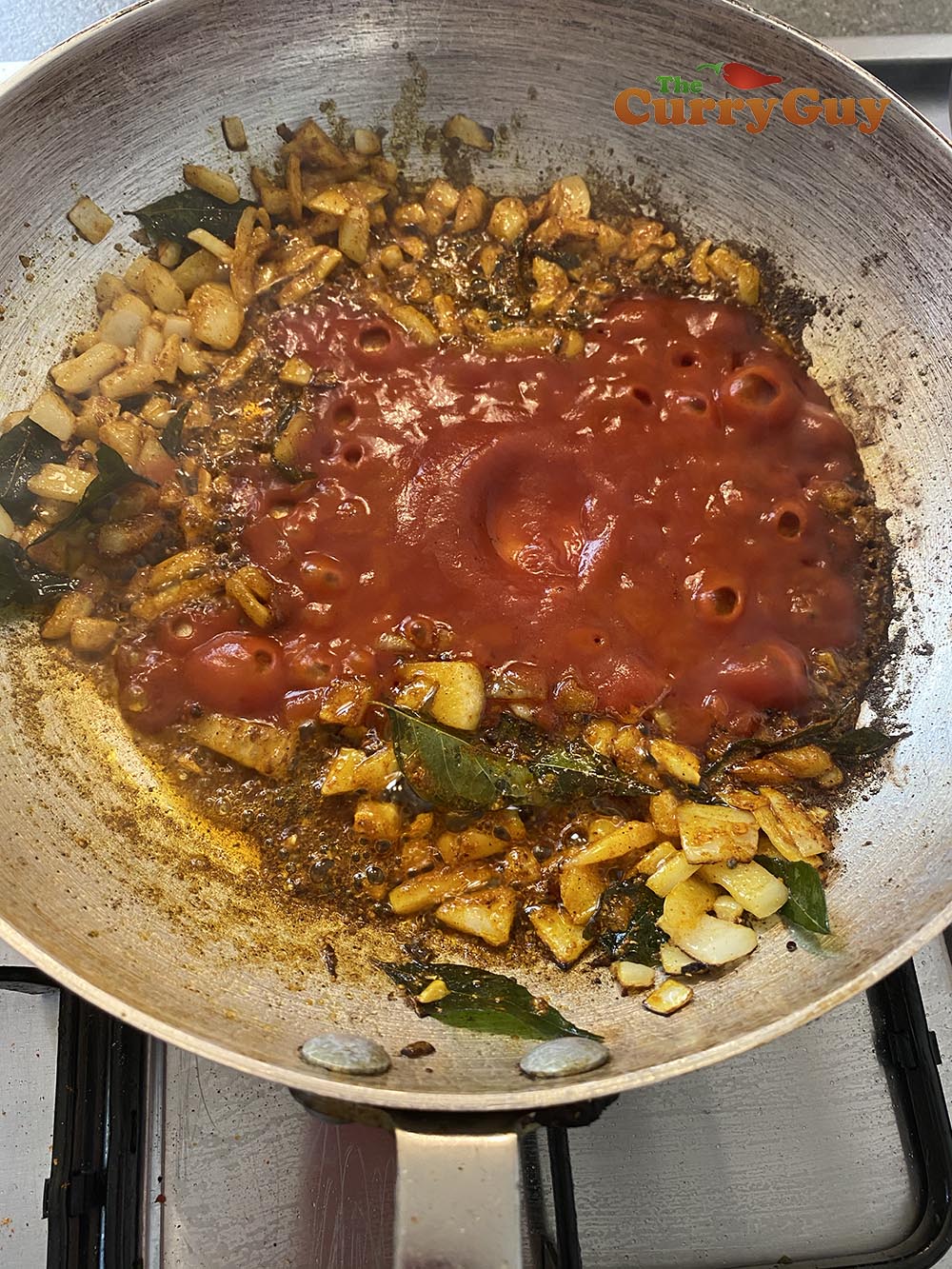 adding tomato puree to the pan