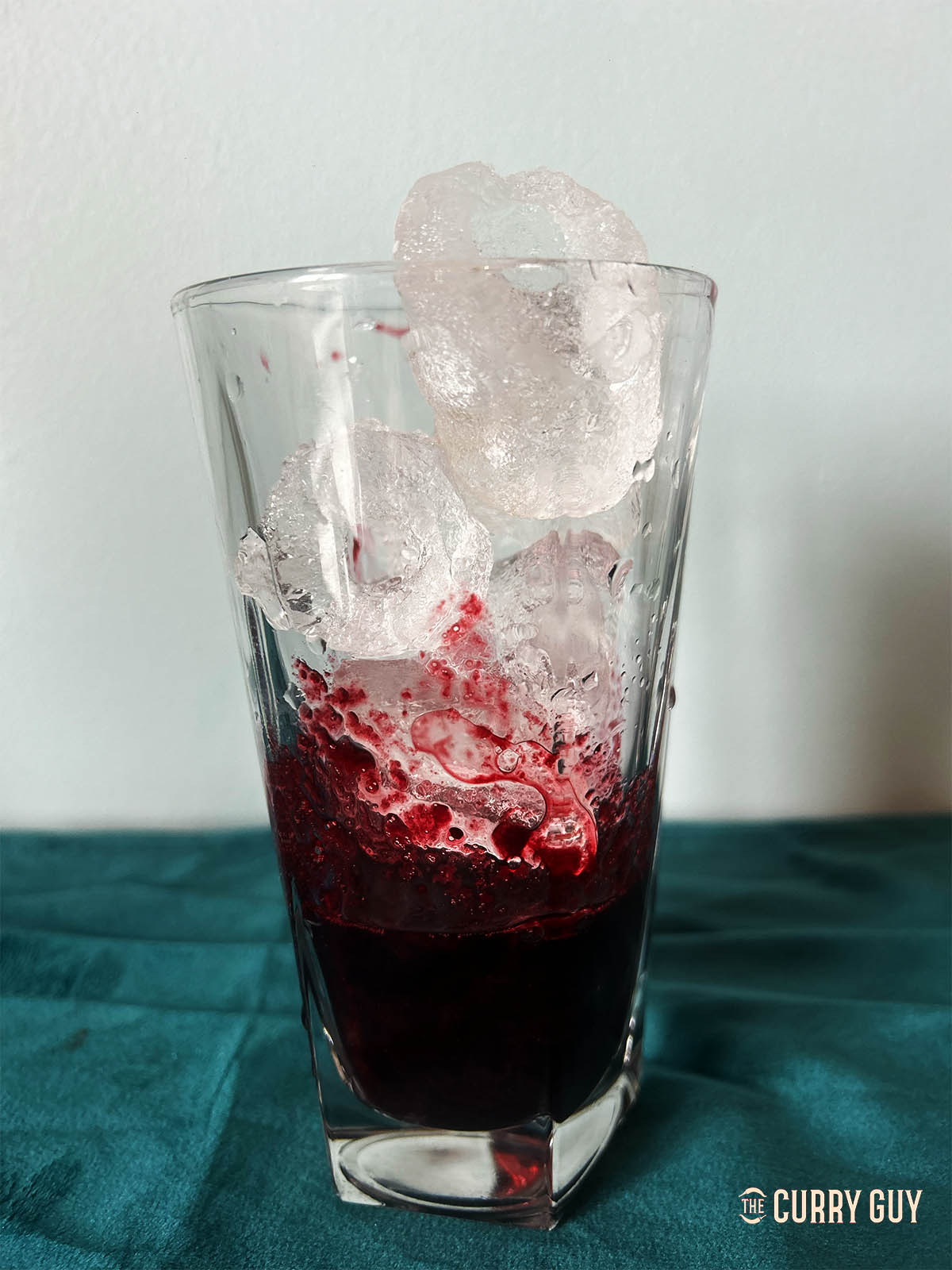 Pouring a serving of the syrup over ice cubes in a tall glass. 