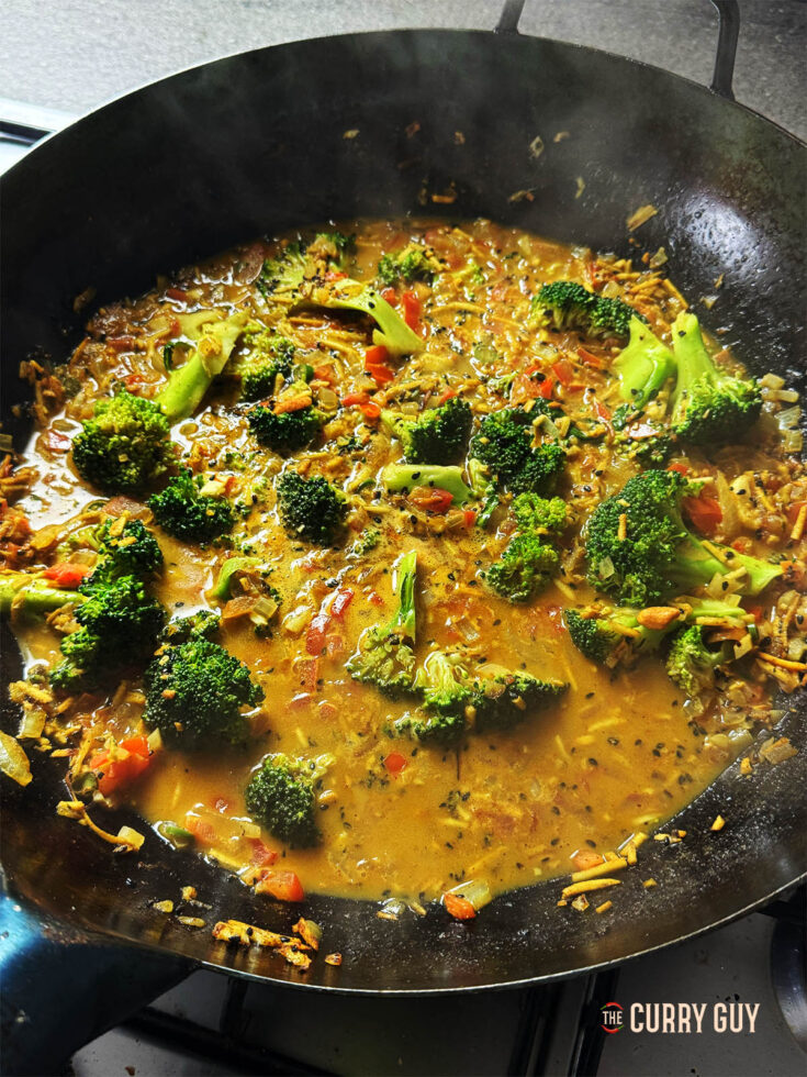 Broccoli curry in a wok, simmering on the stove.