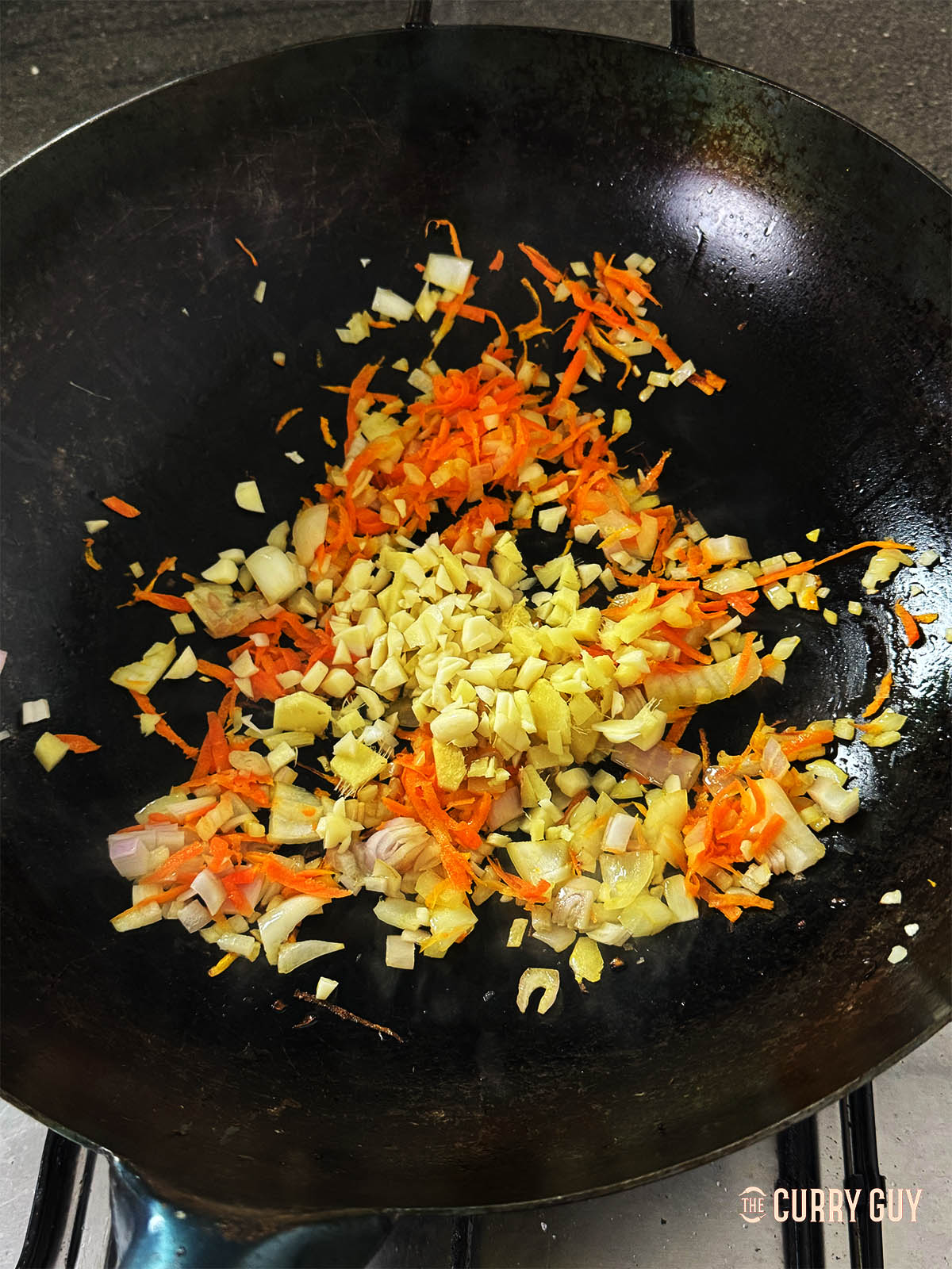 Adding the chopped garlic and ginger to the wok.