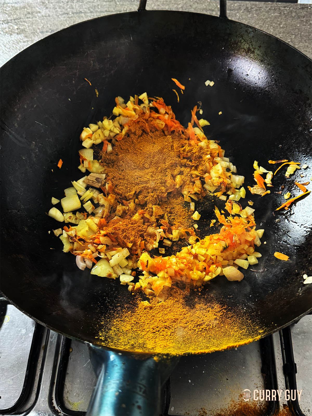 Adding the flour and curry powder to the wok.