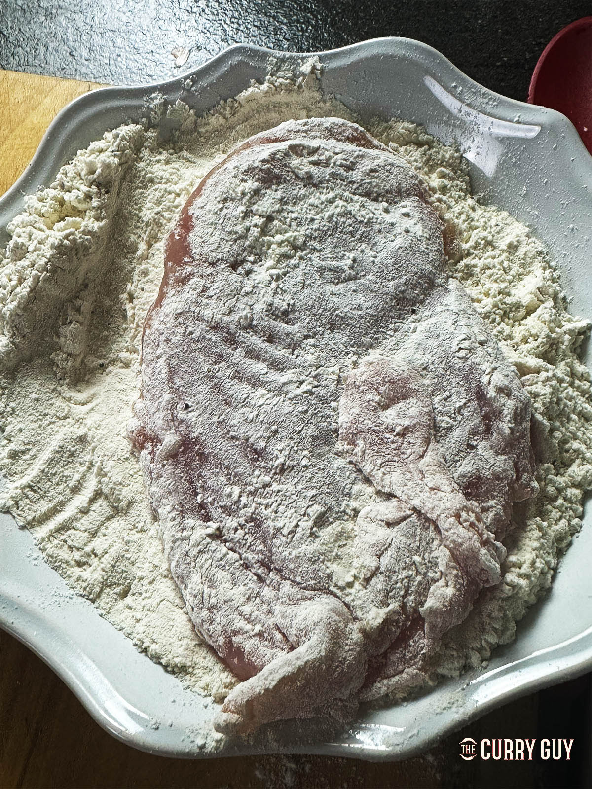 Dredging a chicken breast in the flour, salt and pepper mixture. 