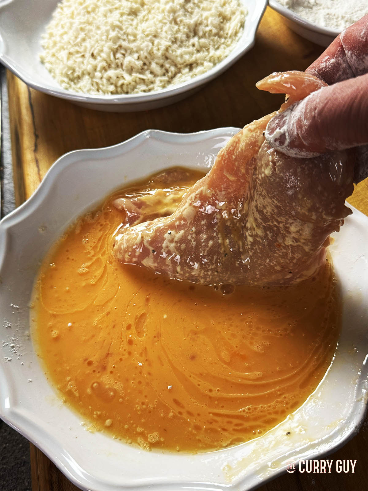Dipping a flour dusted chicken breast in whisked egg.