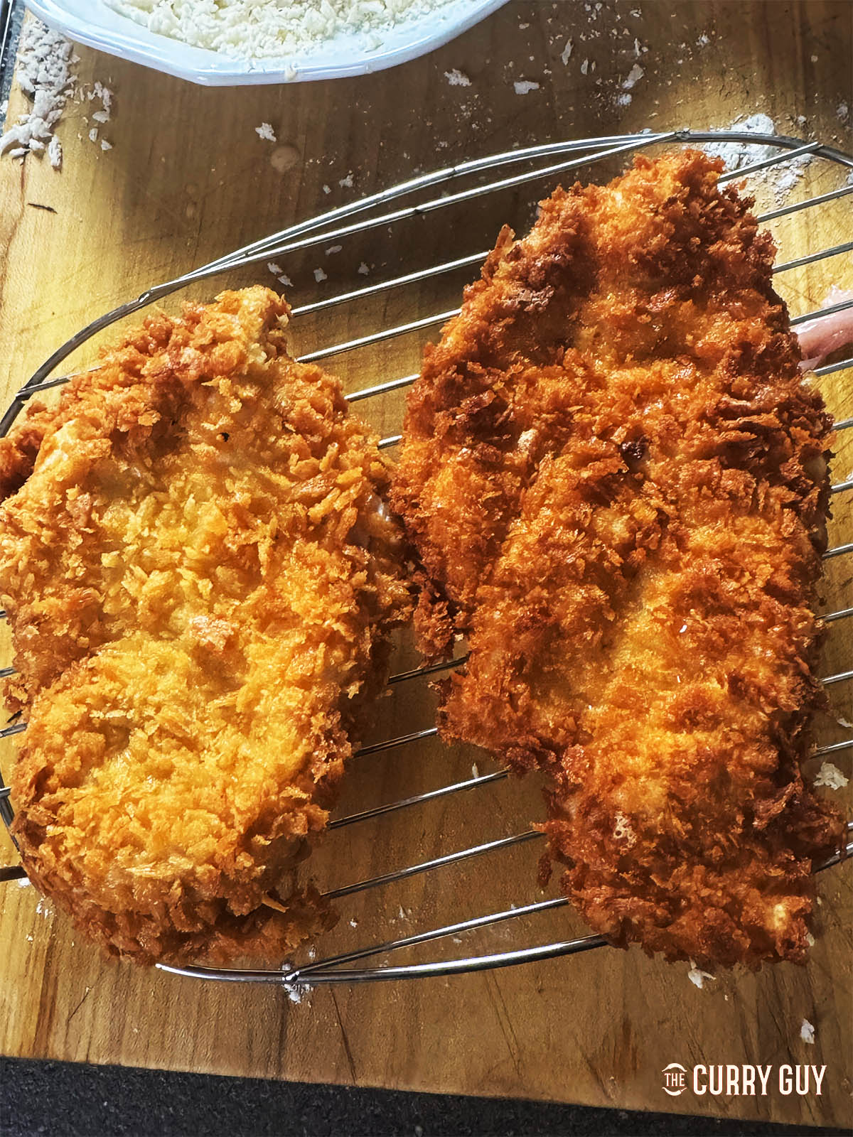 Two chicken katsu breasts on a wire rack. 