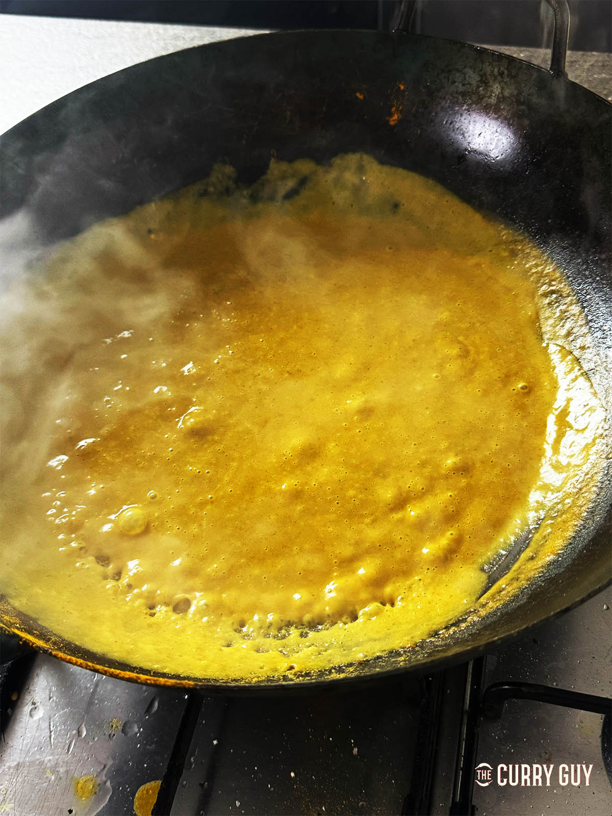 Returning the blended sauce to the wok to simmer.