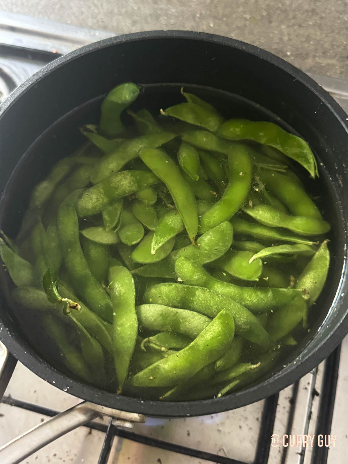 Adding edamame to a pot of boiling salt water.