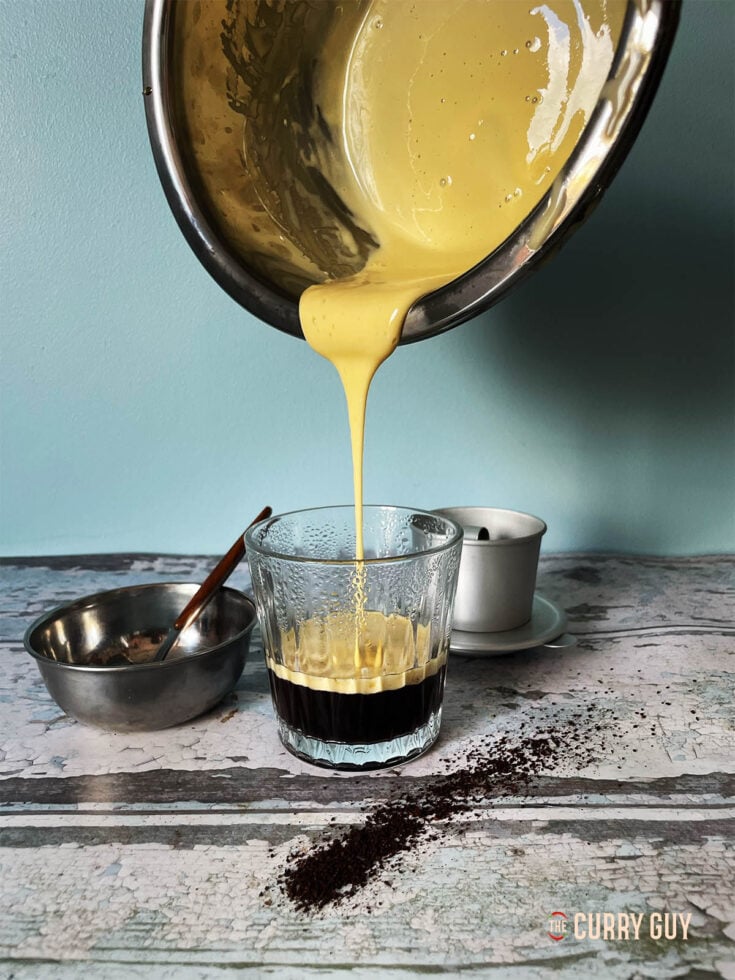 The creamy egg yolk mixture being poured over freshly brewed coffee.