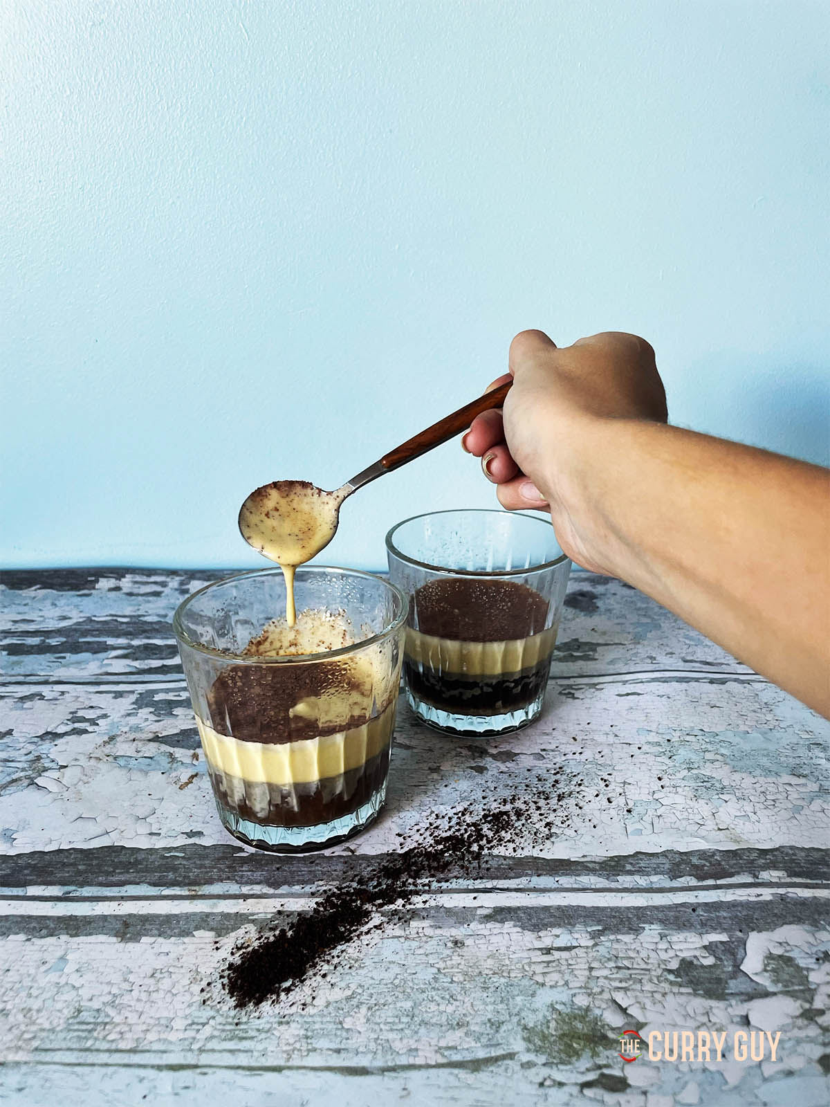 A spoon showing how thick and creamy the egg yolk custard is on top of the coffee.