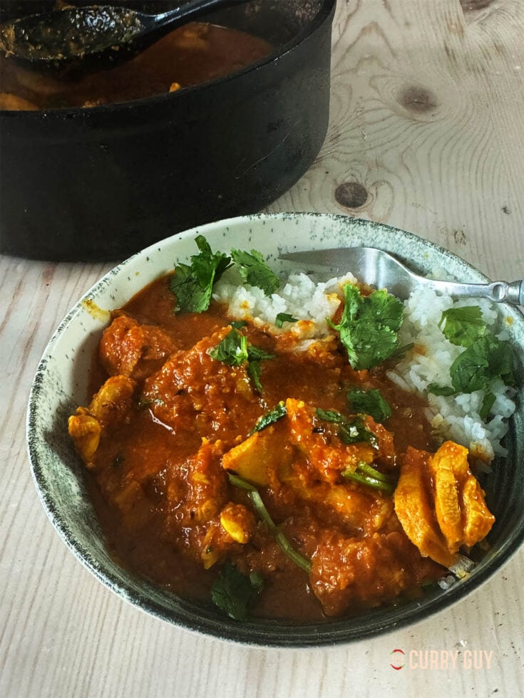 Garlic chicken curry in a serving bowl with rice.