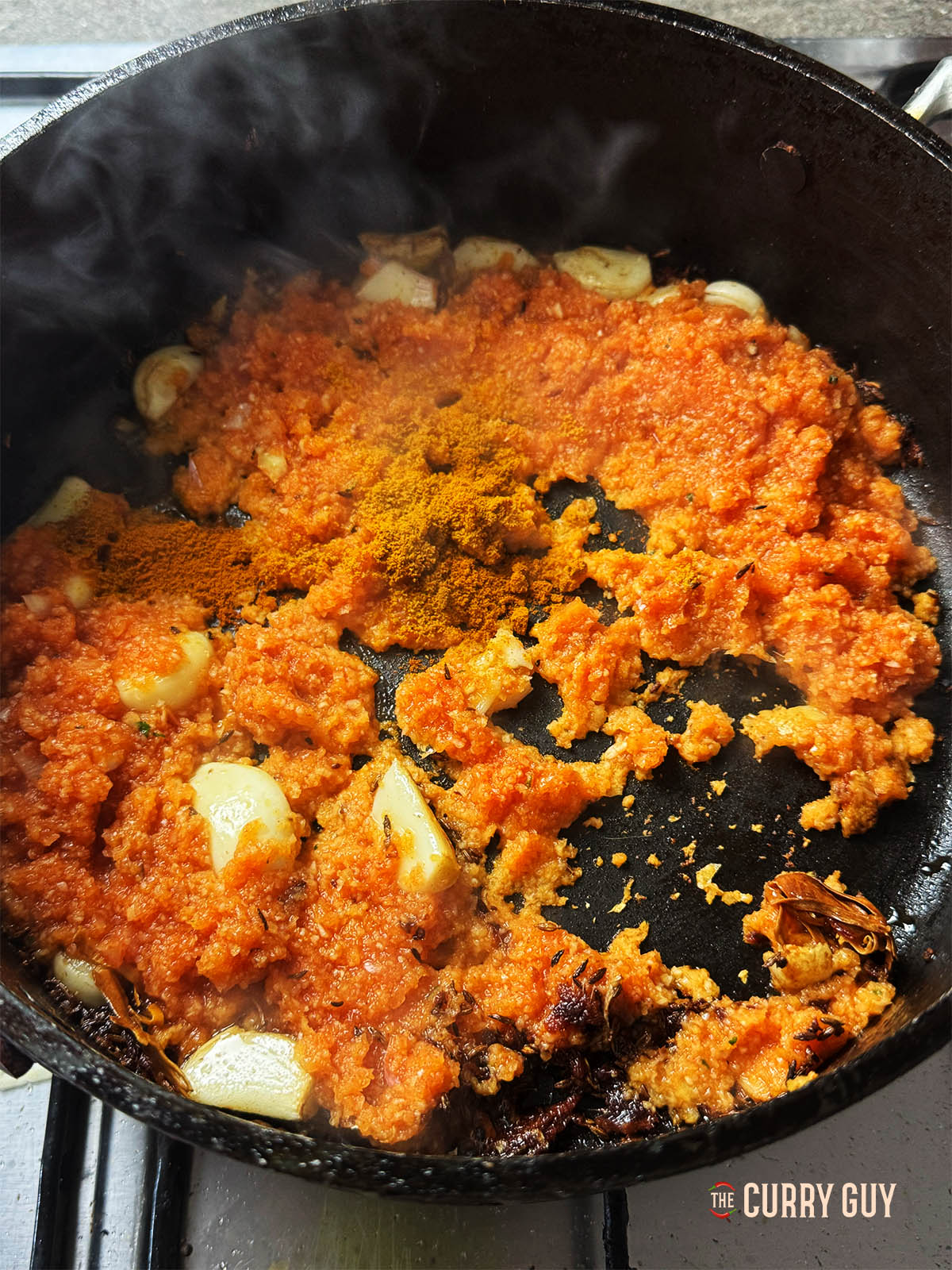 Adding the onion and garlic paste to the pan with the remaining paprika.
