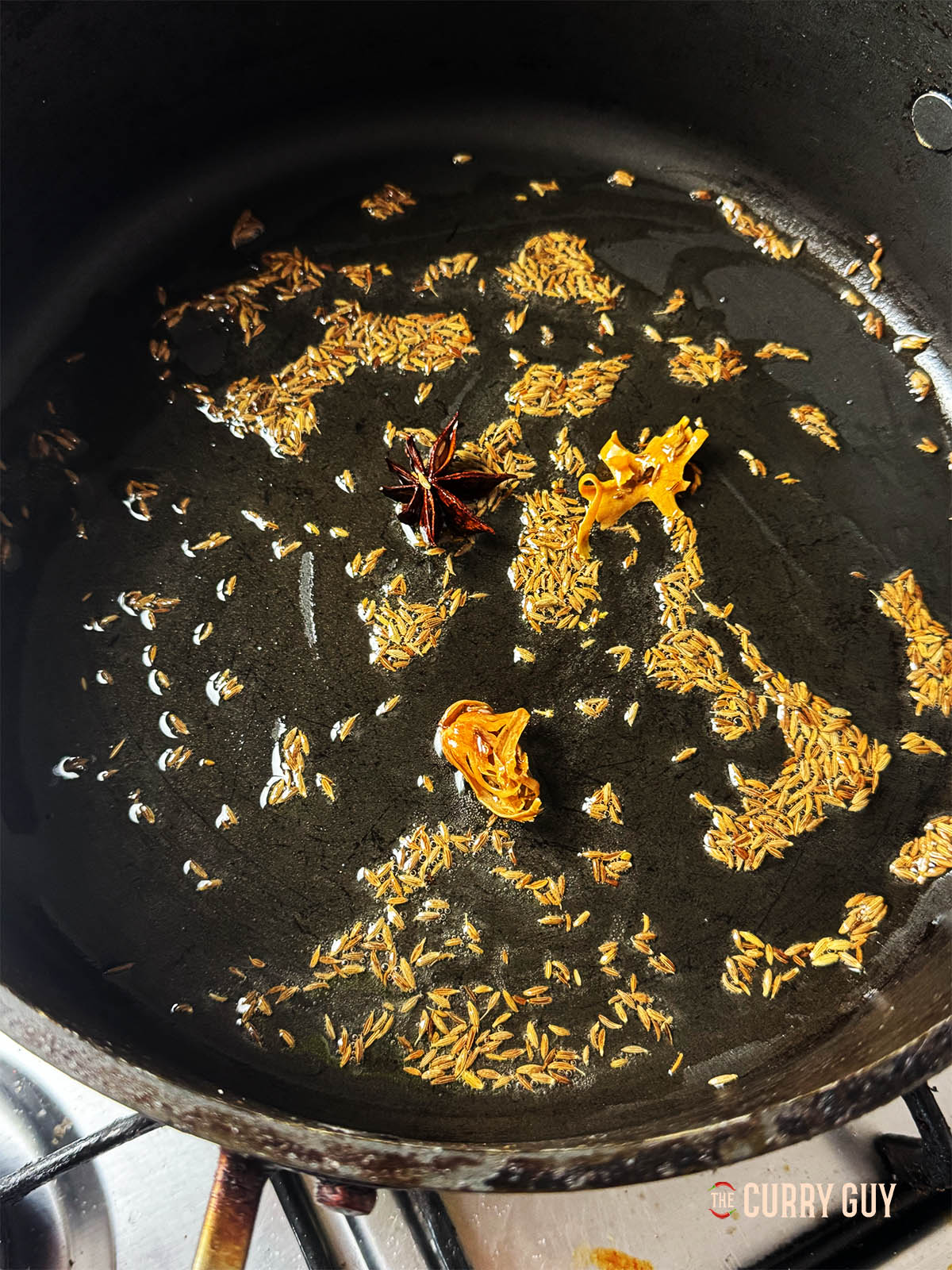 Infusing the mace, star anise and cumin seeds in oil in a pan for about 30 seconds.