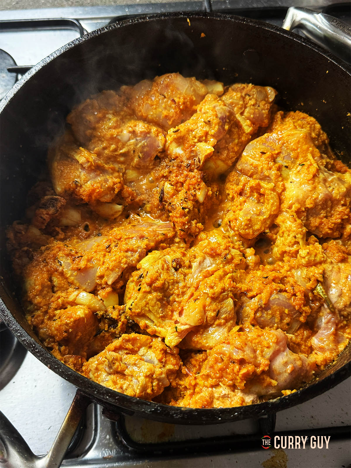 Adding the chicken with its marinade to the pan.
