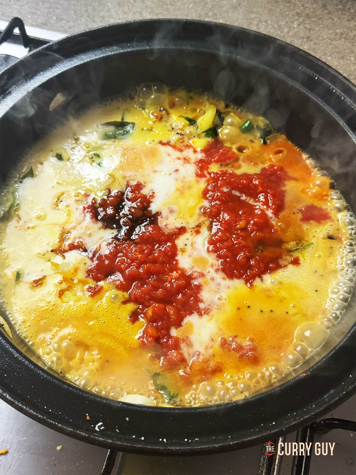 Adding the chopped tomatoes, coconut milk and soy sauce to the pan.