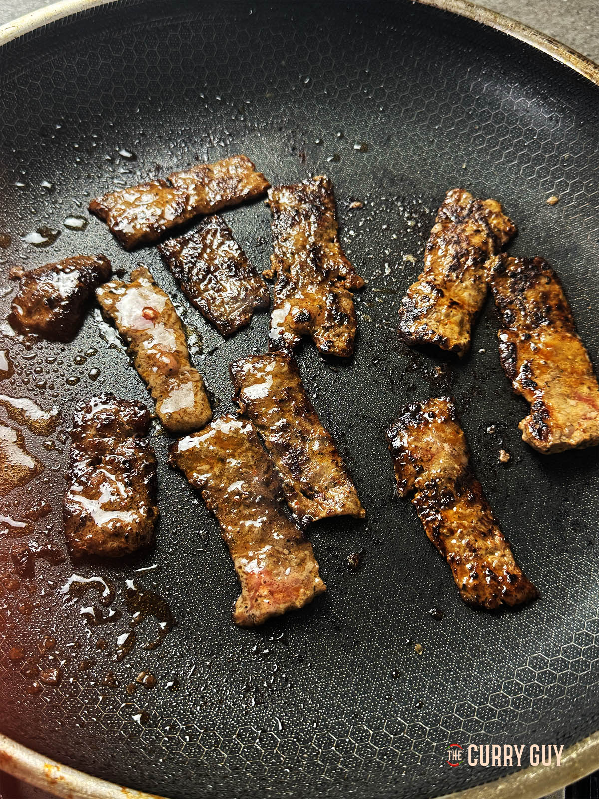 The charred meat in a pan.