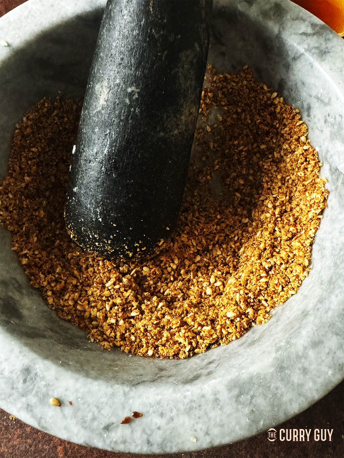 Grinding the sesame seeds in a pestle and mortar.
