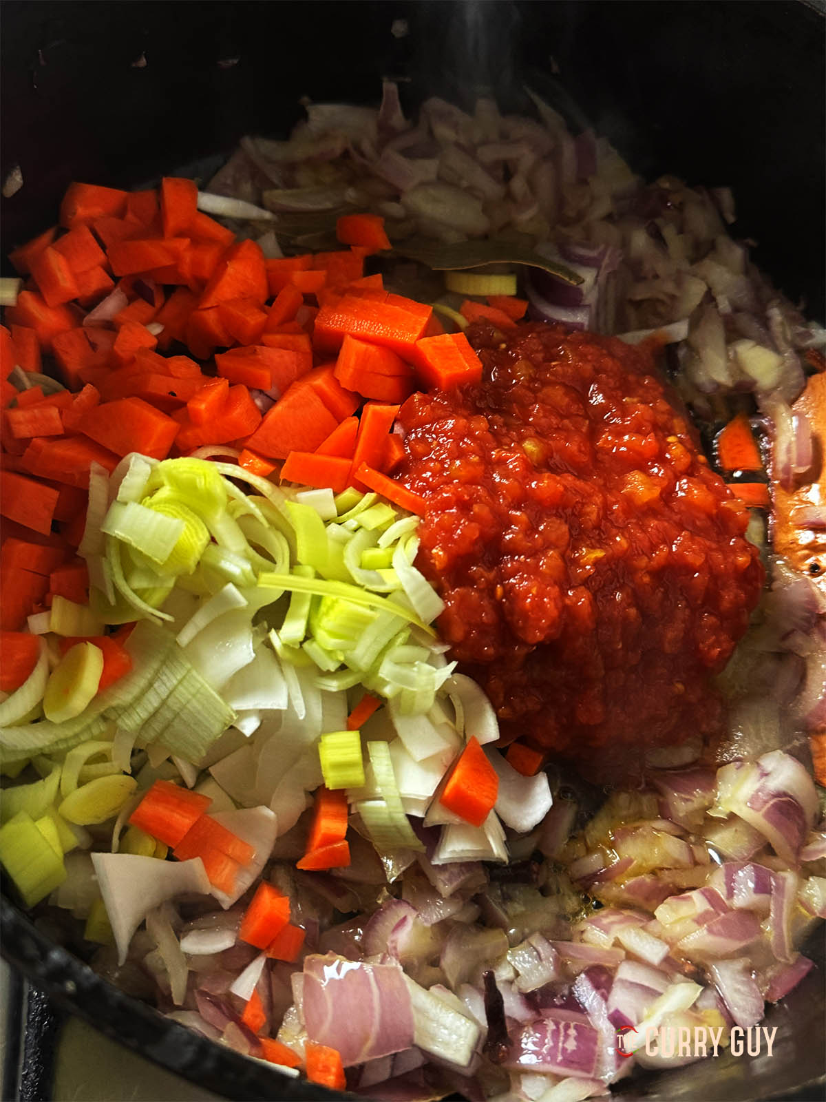 Adding the tomatoes, celery, leeks and carrots to the onion mixture.