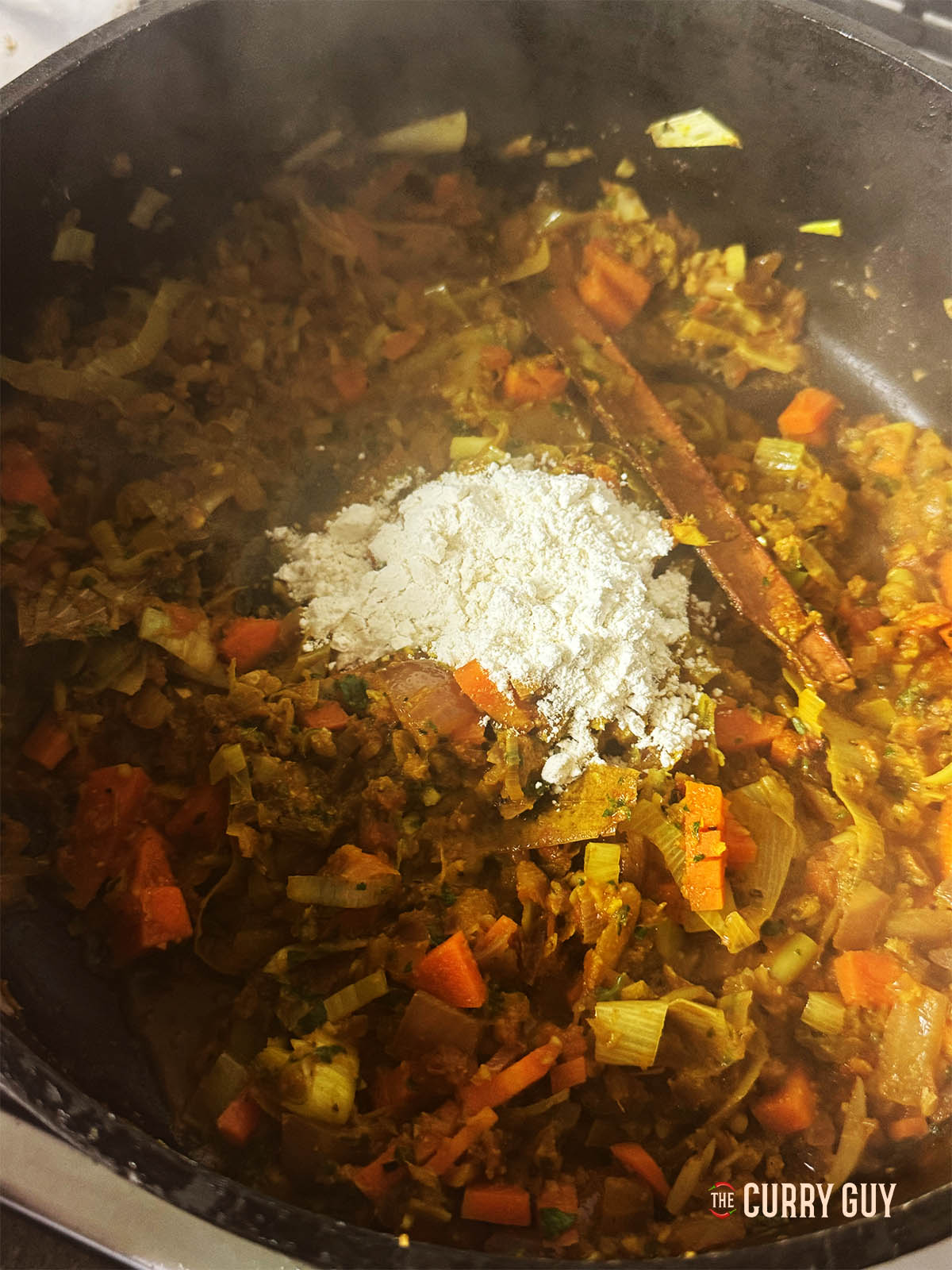 Adding the flour to the vegetables in the pot.