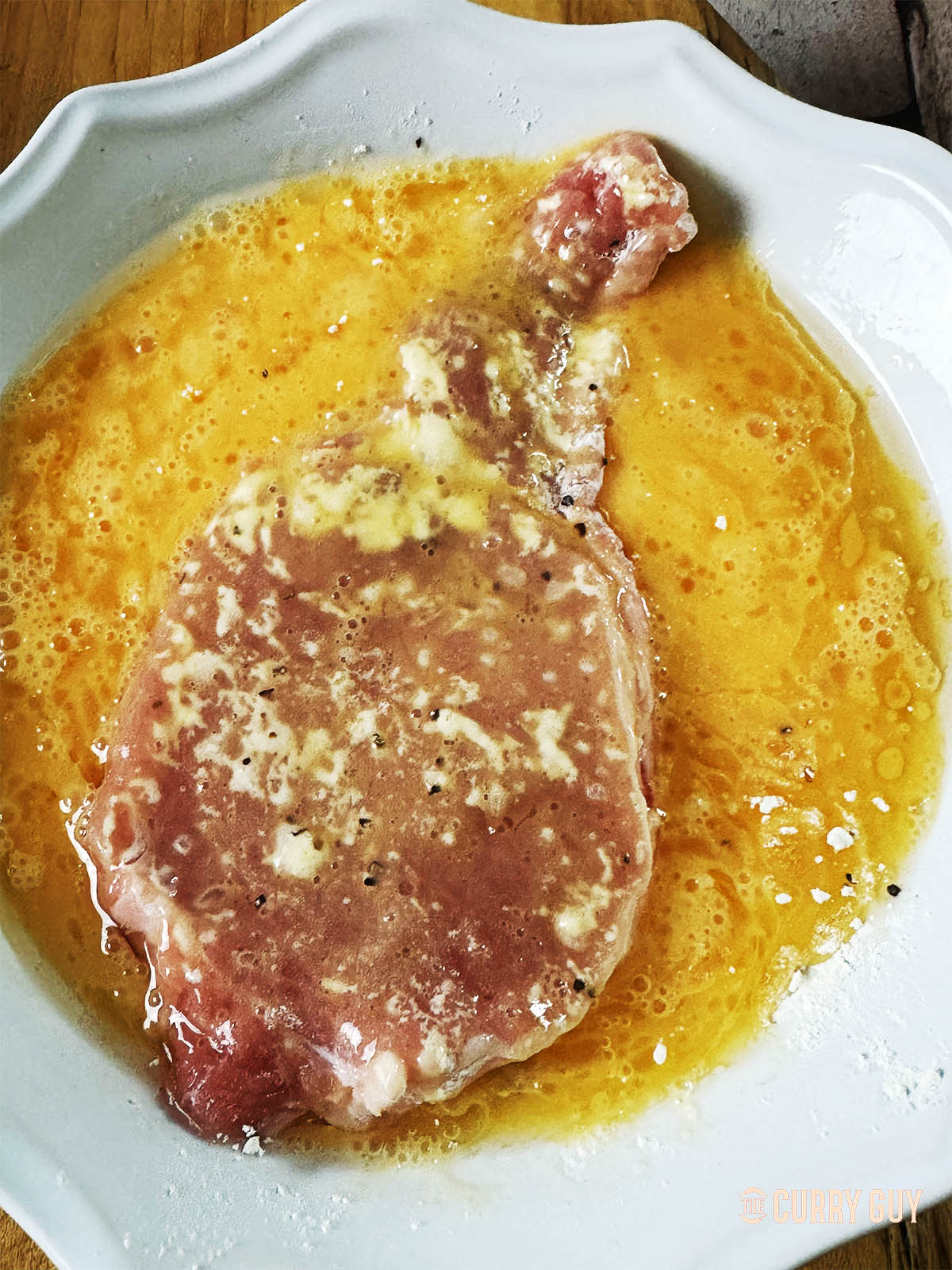 Dipping a pork loin chop in the beaten eggs.