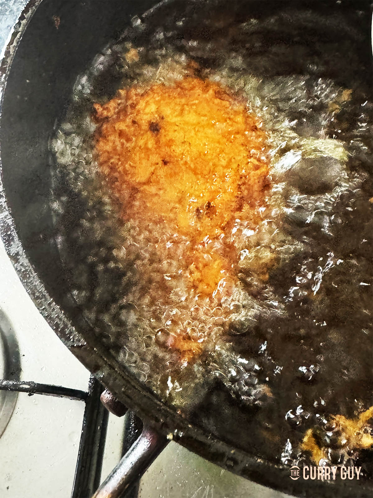 Adding a breaded tonkatsu to hot oil to cook.