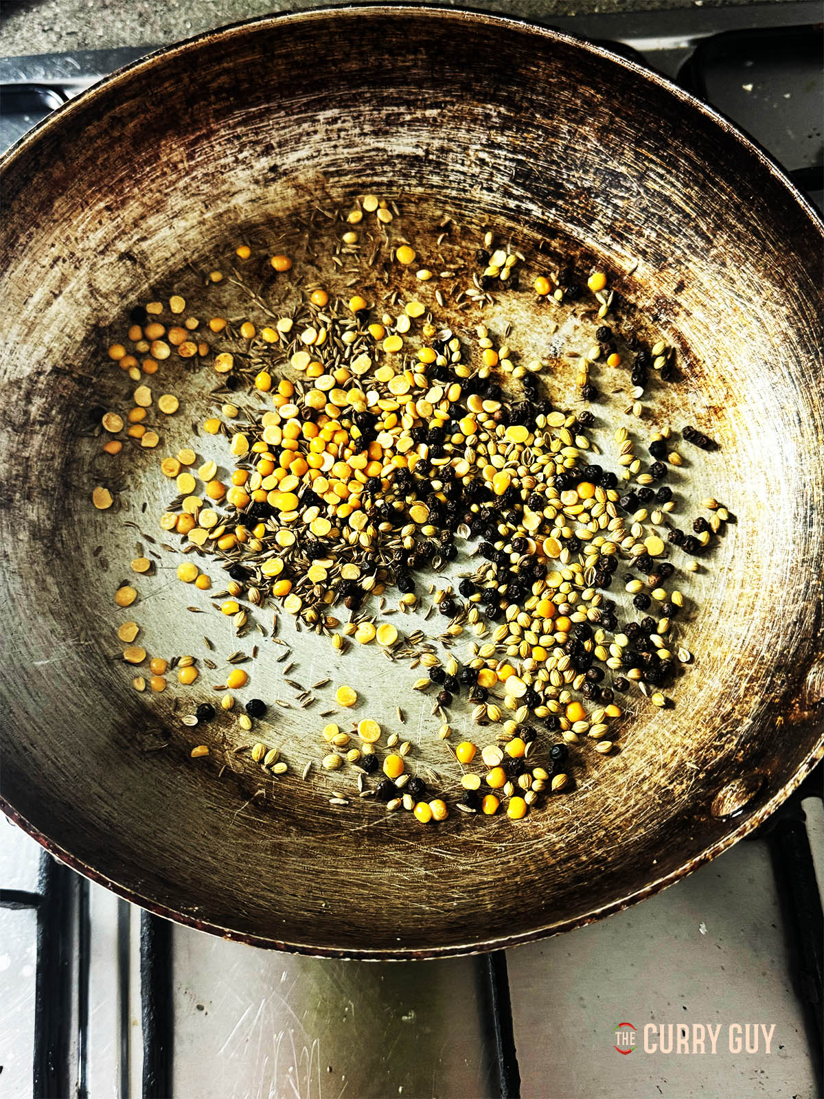 Toasting the cumin seeds, coriander seeds, toor dal and black pepper corns until fragrant.