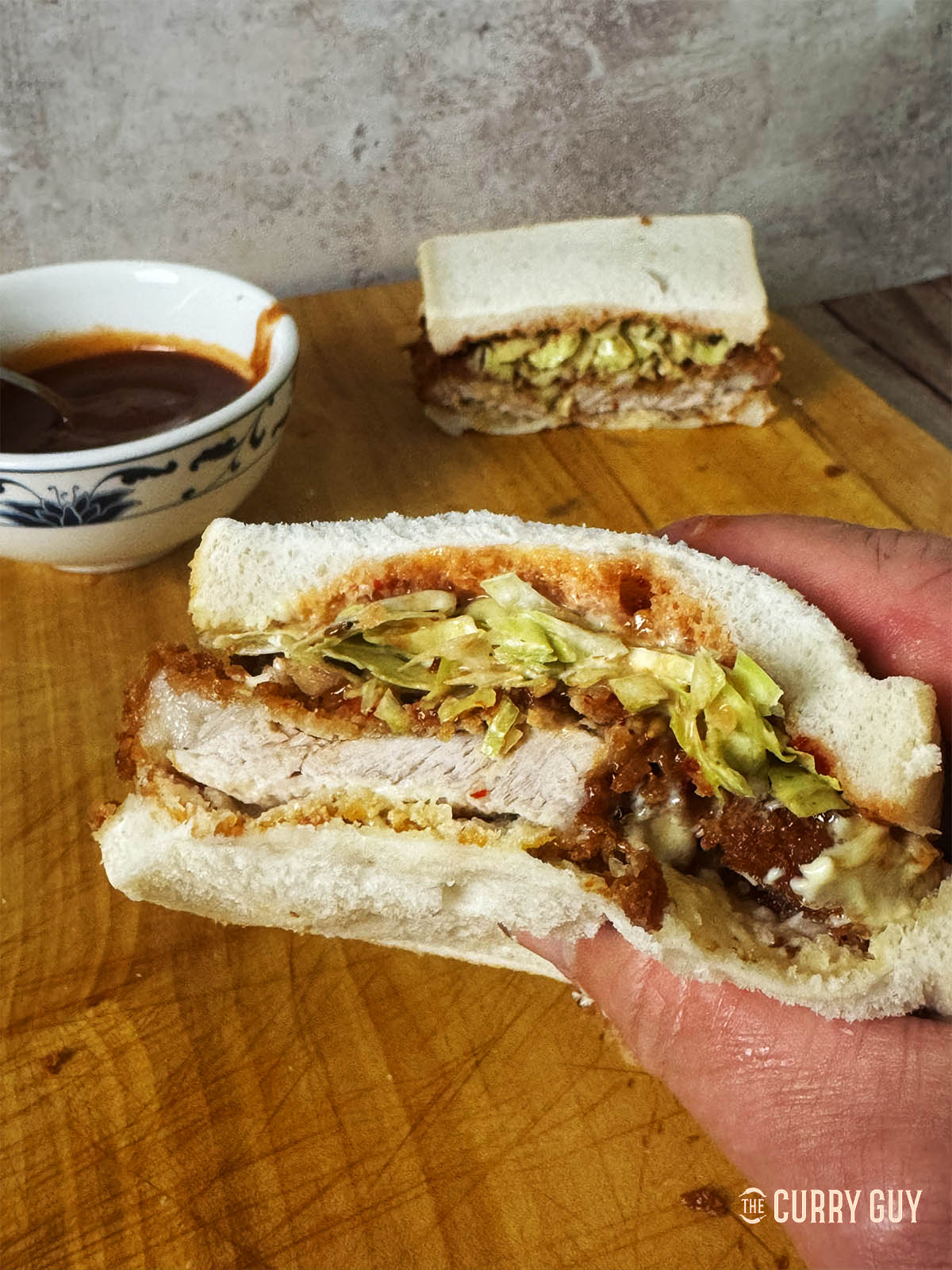 Holding a katsu sando to eat it. 