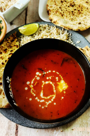 Spicy tomato soup, garnished with a drizzle of coconut milk.