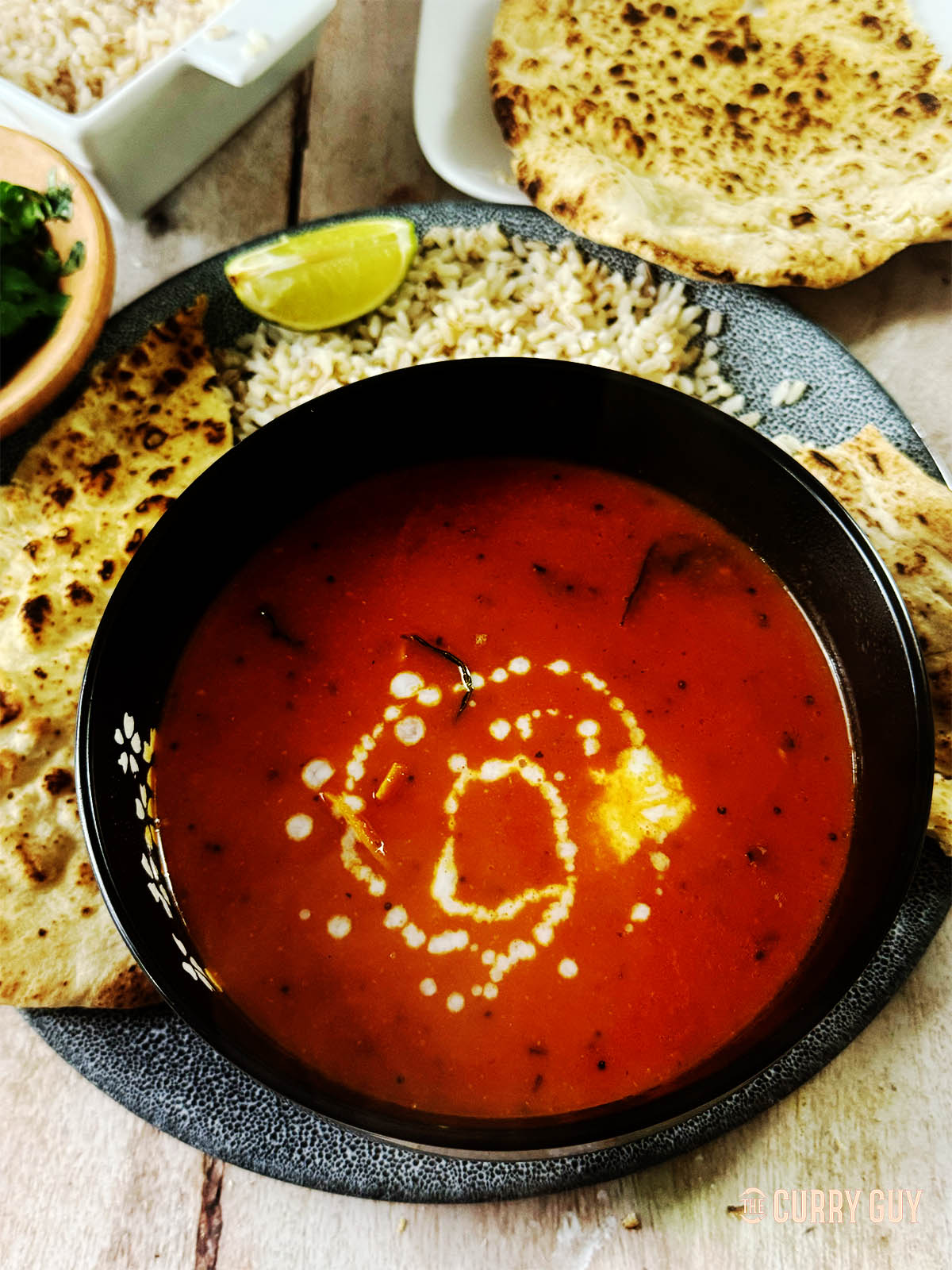 Spicy tomato soup, garnished with a drizzle of coconut milk.