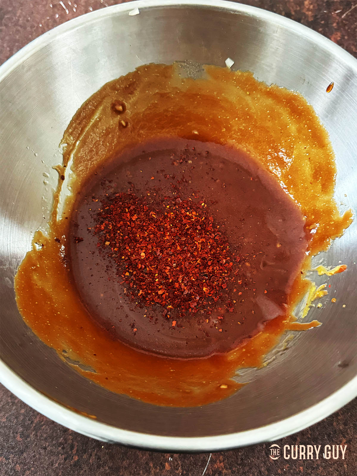Adding chilli flakes to the sauce.