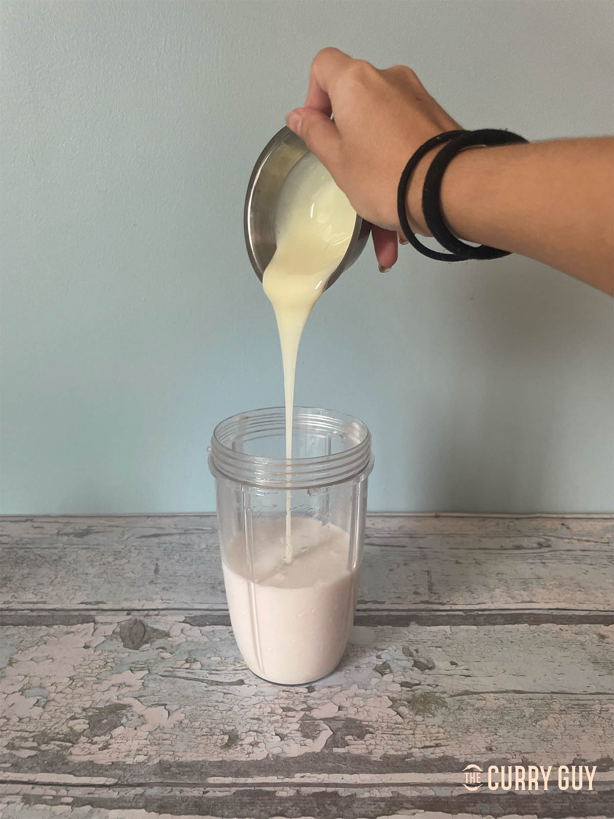 Pouring the condensed milk and coconut milk into a blender