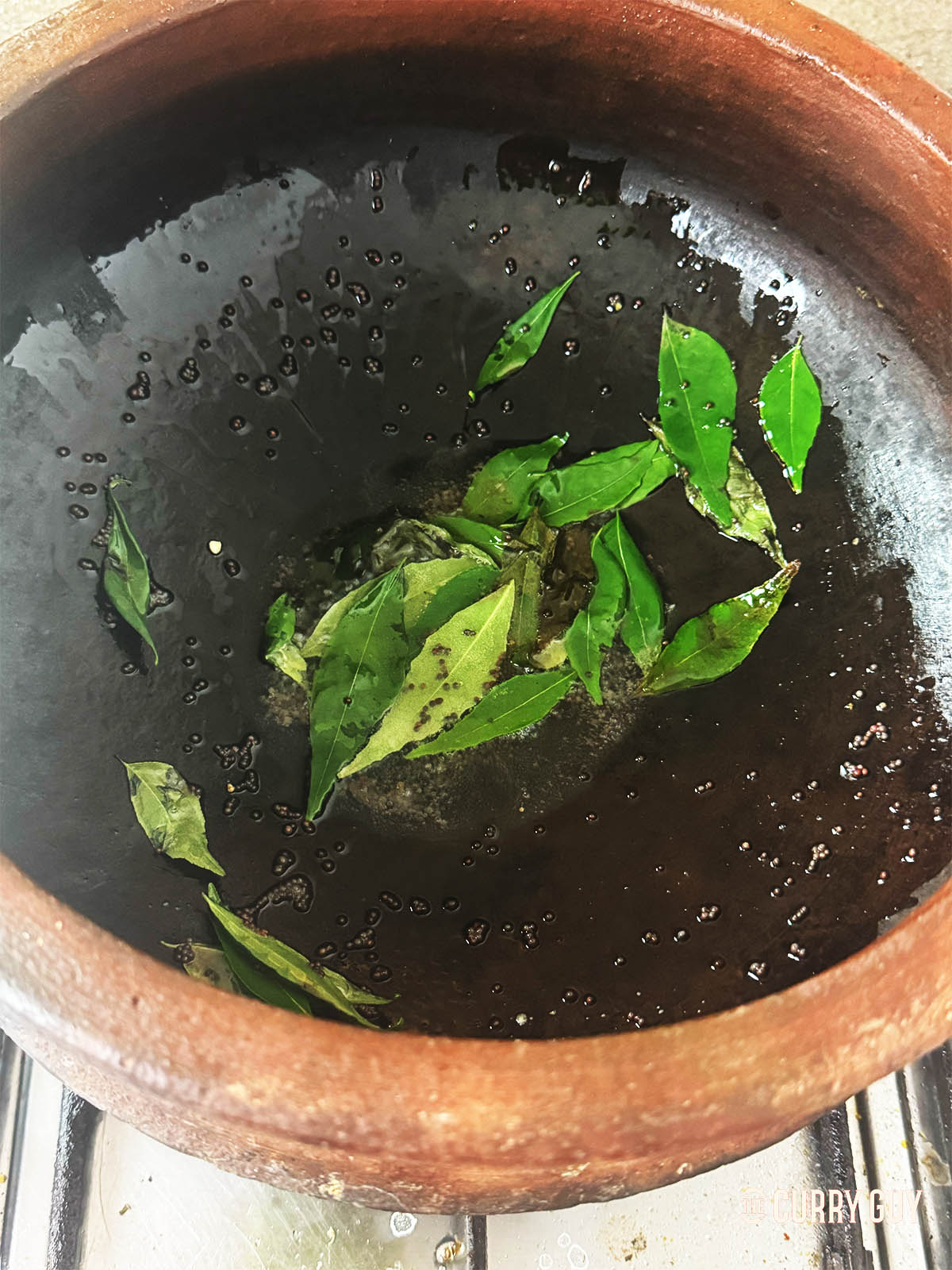 Frying the mustard seeds and curry leaves in oil.