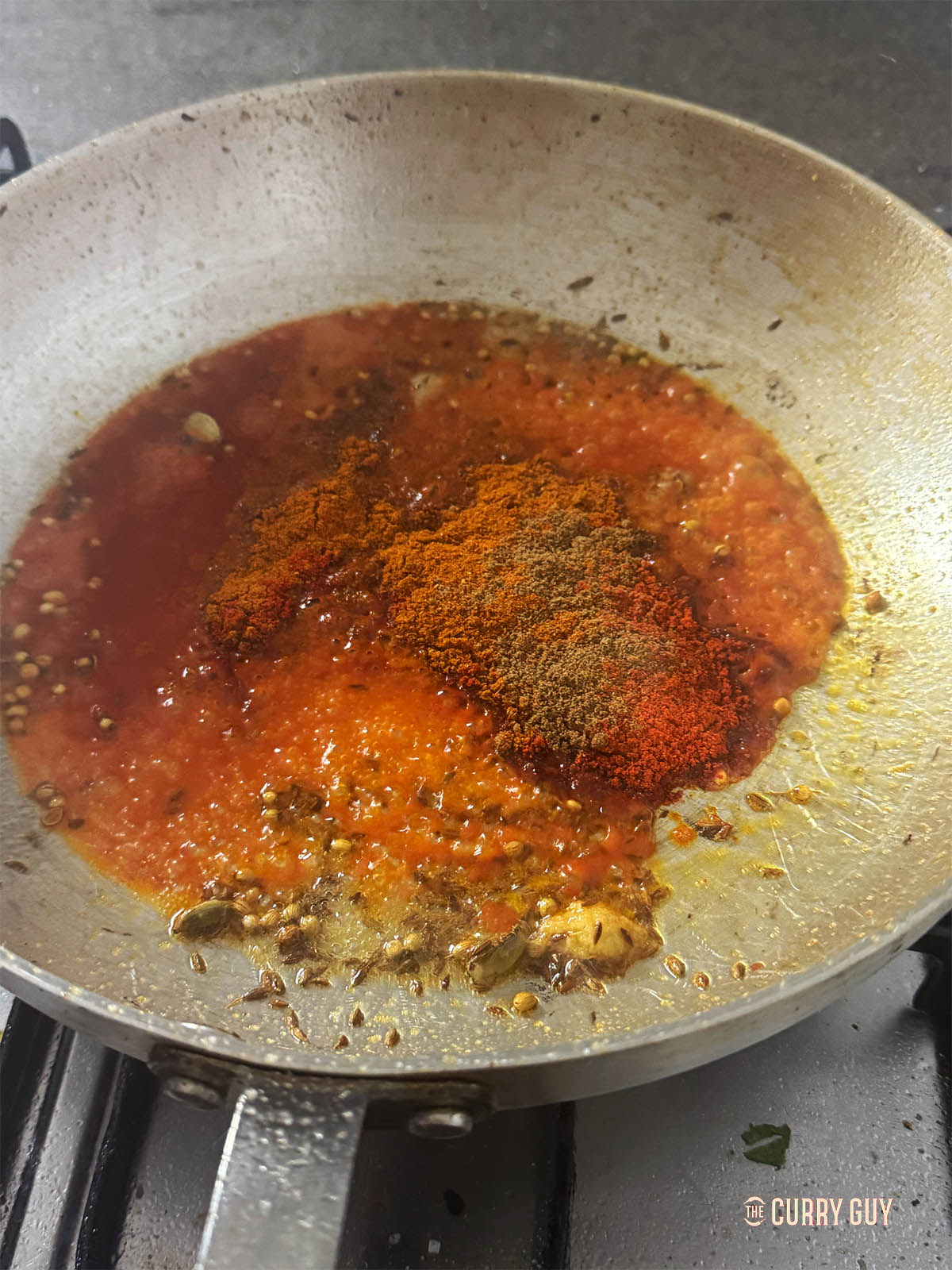 Adding the tomato purée and ground spices.