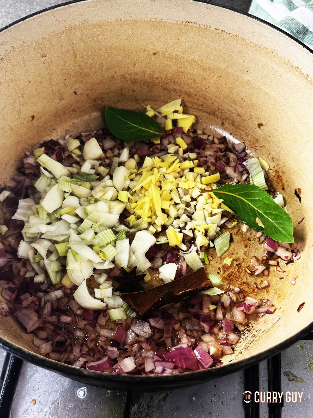 Adding the garlic, ginger, spring onions and bay leaves to the frying onions.