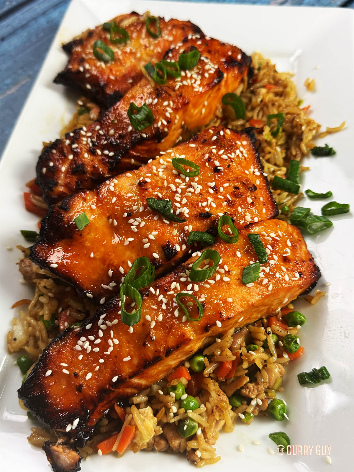 The cooked miso salmon on a bed of rice, garnished with sesame seeds and spring onions. 