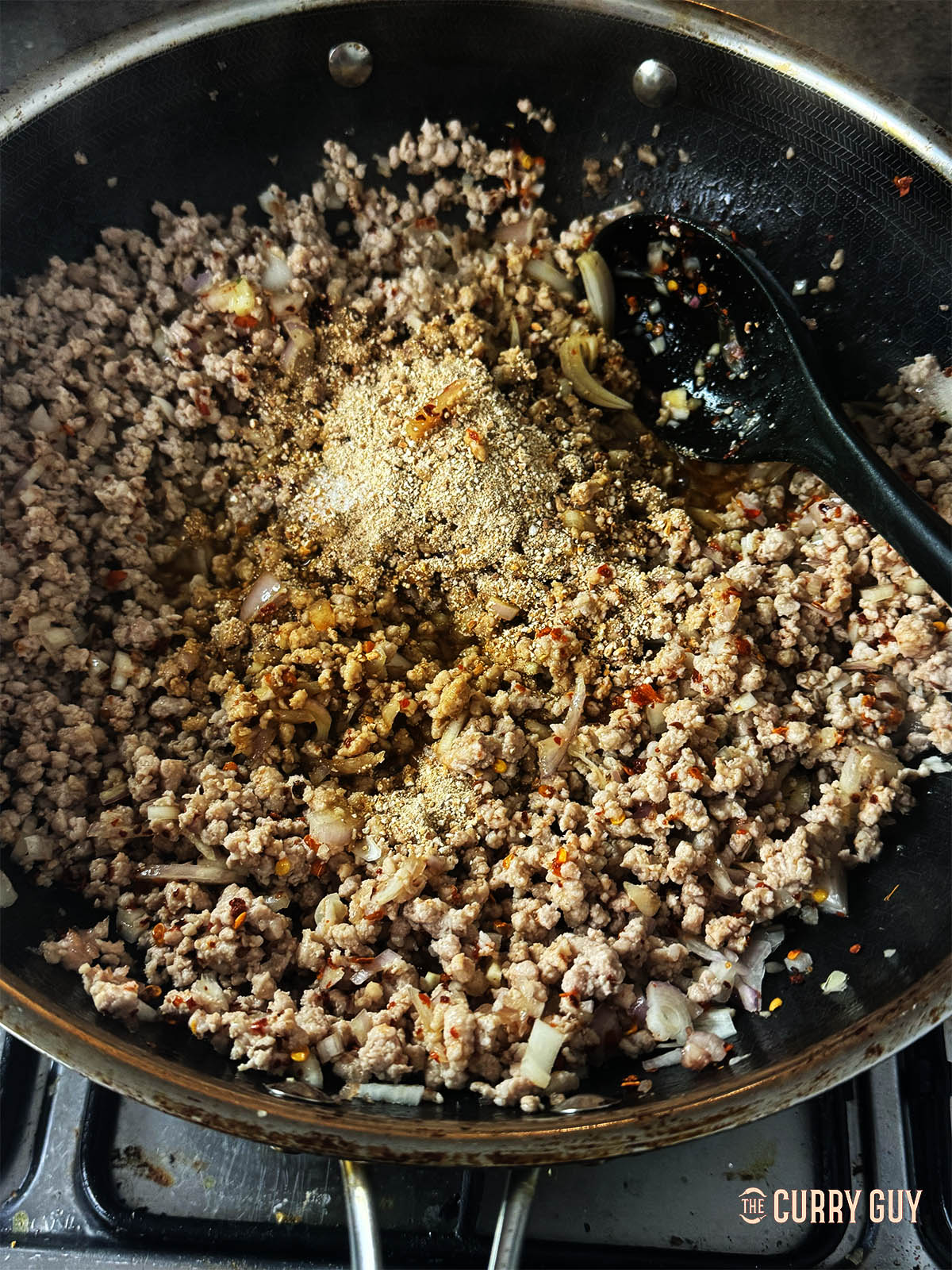 Adding the khoa khua, fish sauce and soy sauce to the pork in the pan.