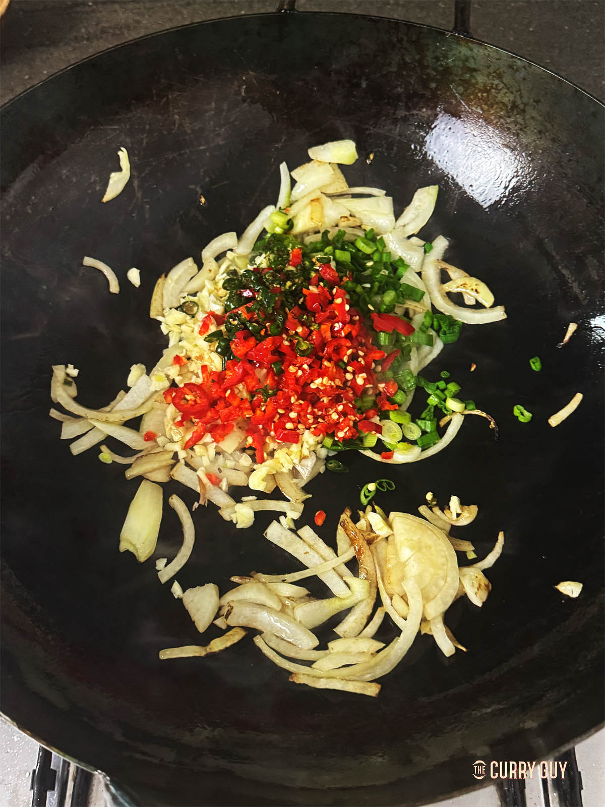 Frying their onion and chillies in the wok.