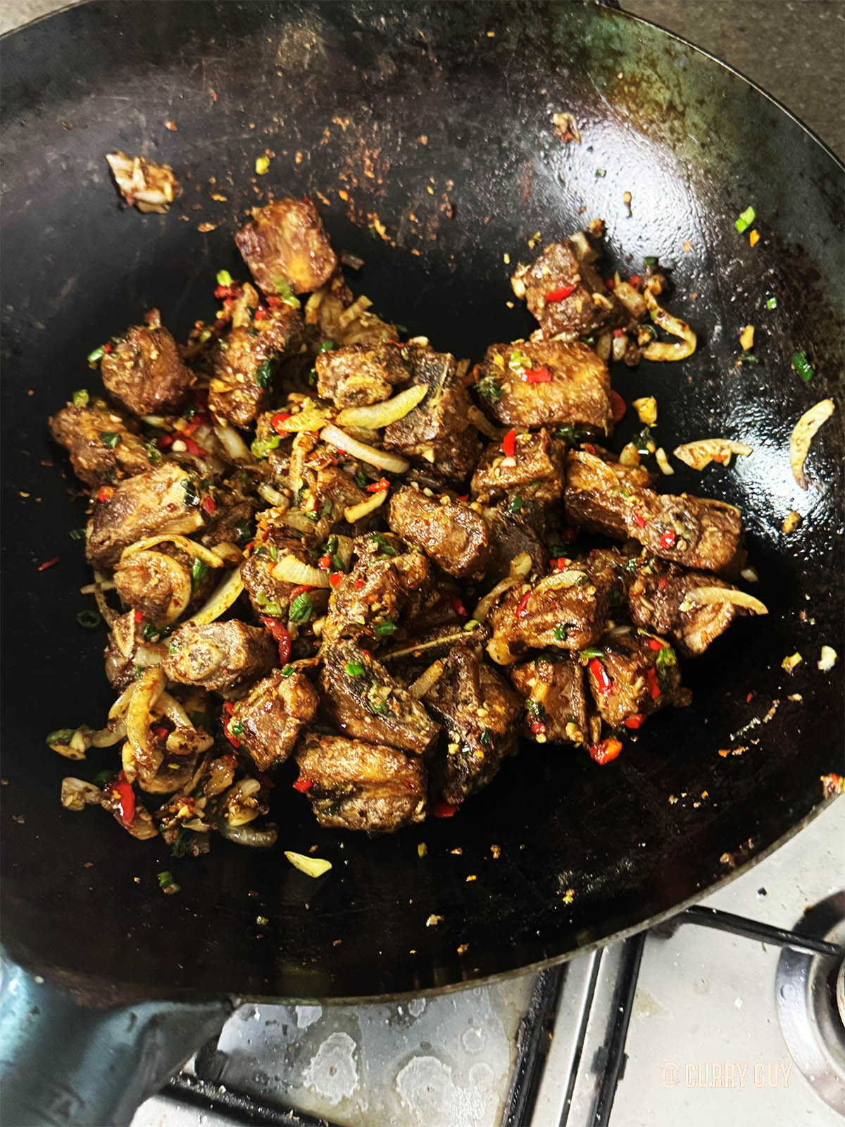 Adding the fried ribs to the ingredients in the wok.