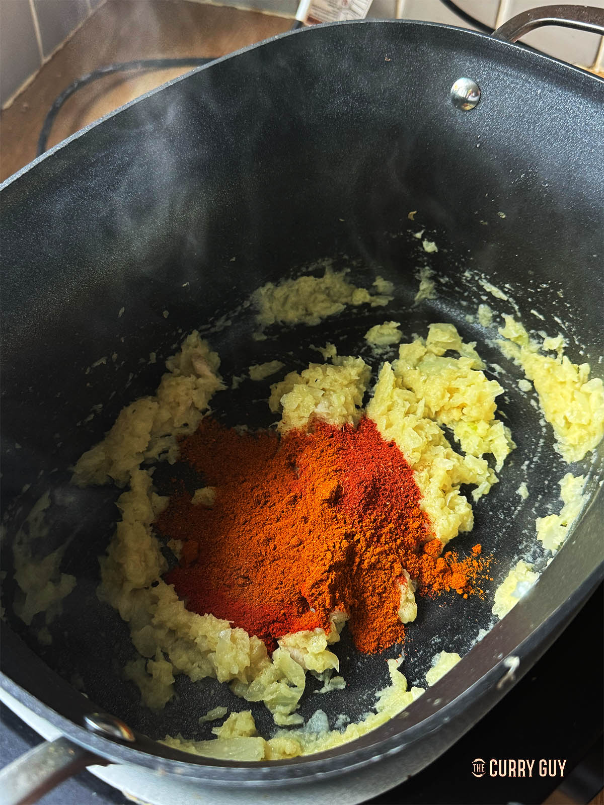 Adding the ground spices to the onion mixture in the slow cooker. 