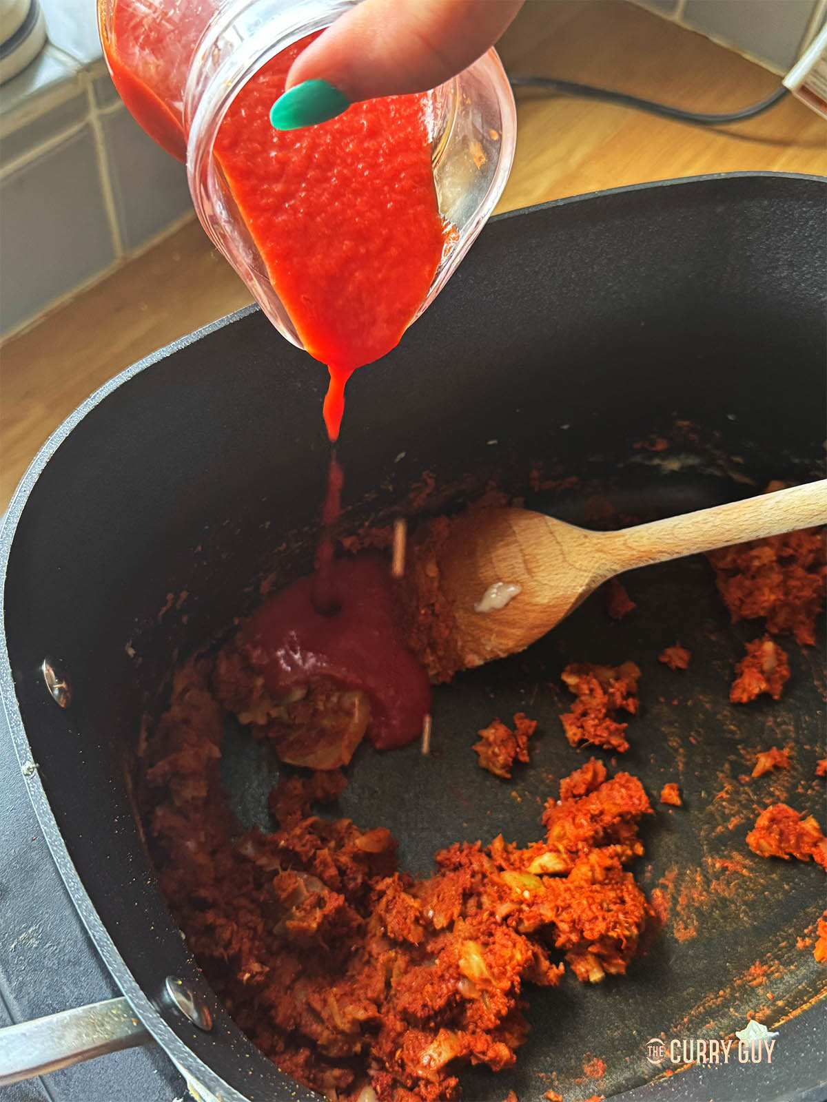 Adding the tomato purée to the onion mixture. 